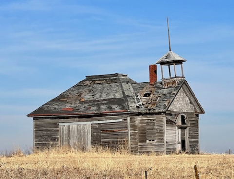 Wooden schoolhouse standing abandonded in a field