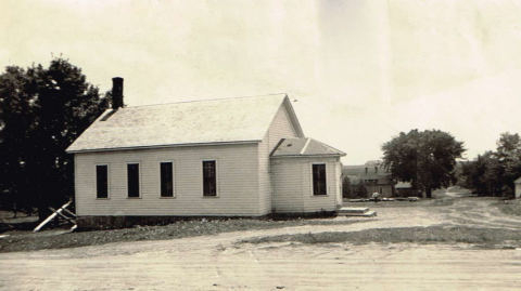 Photo of a white schoolhouse in a town