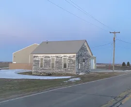 Unpainted schoolhouse during sunset