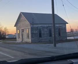 Unpainted schoolhouse during sunset