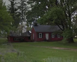 Red schoolhouse sitting amongst trees