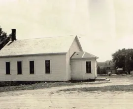 Photo of a white schoolhouse in a town