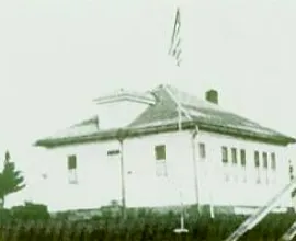 White schoolhouse with a flag